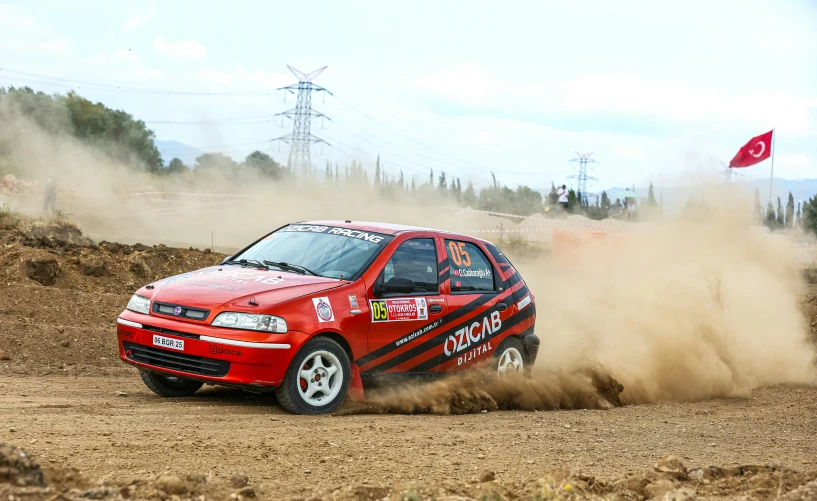 a red car is driving through the dirt