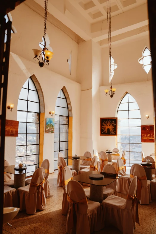 an indoor sitting area with tables and chairs, decorated in linen