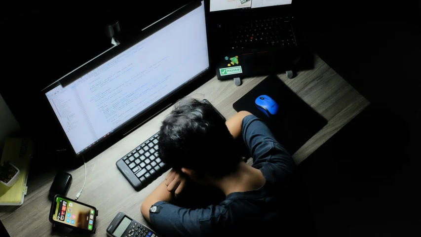 someone laying in front of three computer screens