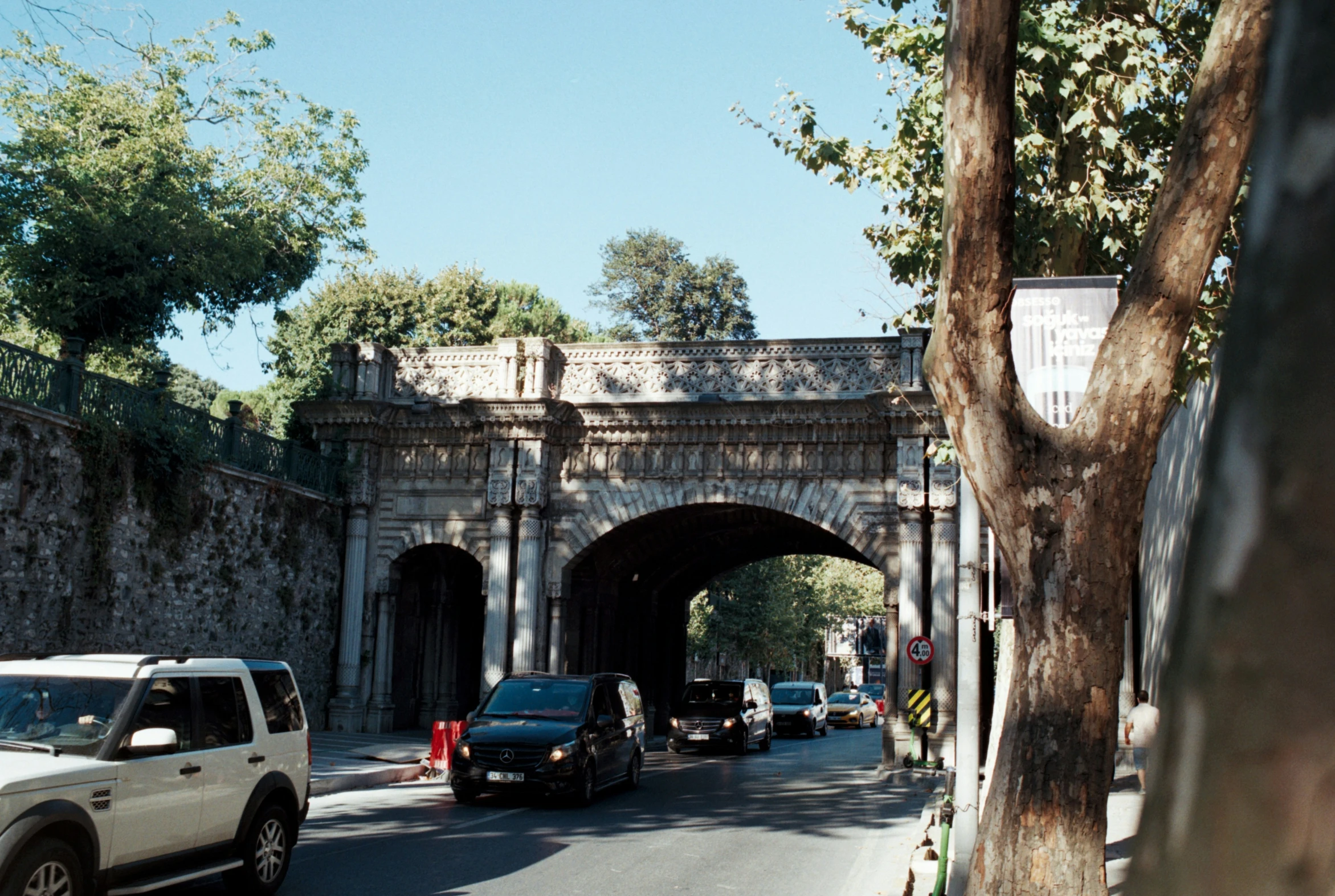 a street scene with cars parked near an old bridge