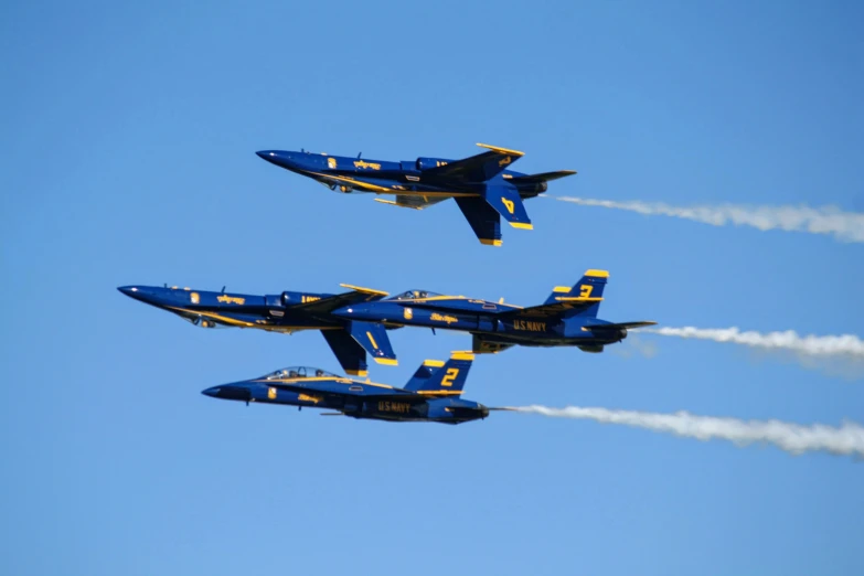 four jets fly in formation with smoke behind them