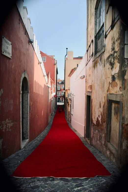 an archway leads to an empty alley with a red carpet