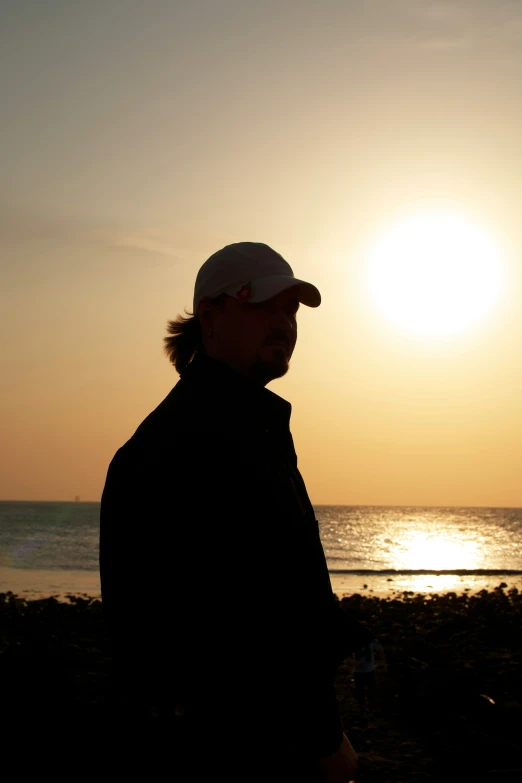 a man wearing a cap at sunset on a beach