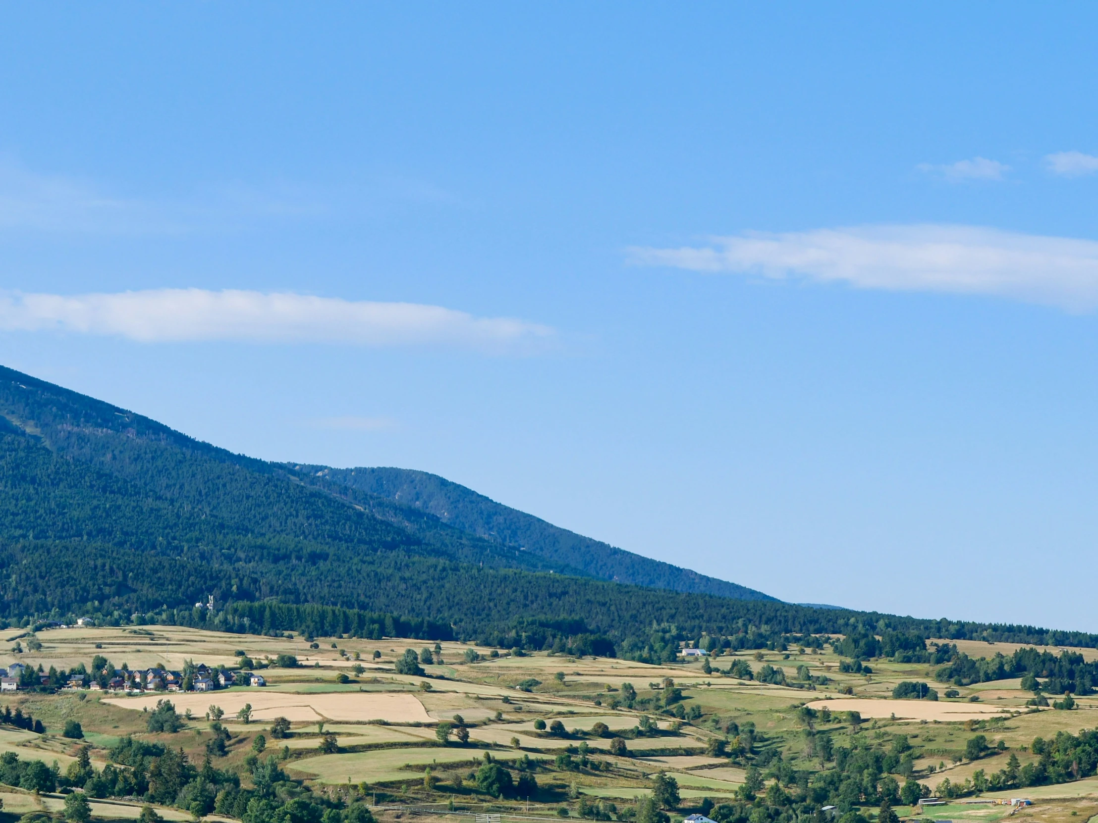 a farm land surrounded by mountains and hills