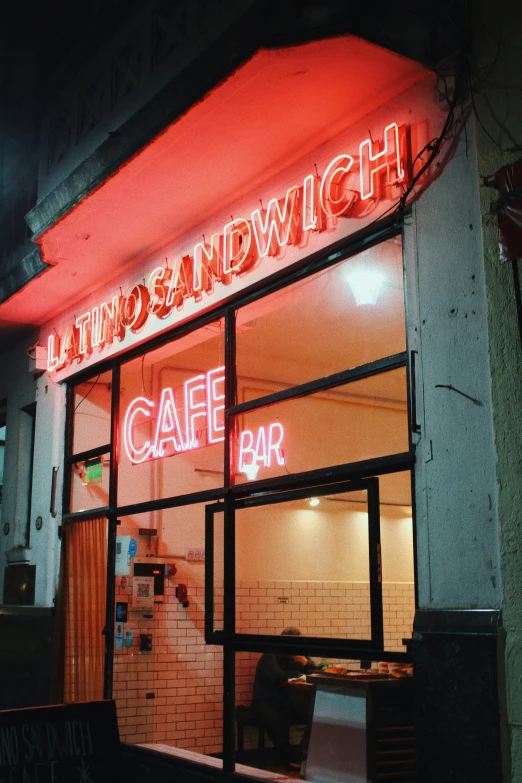 the outside of a cafe at night with red neon lights