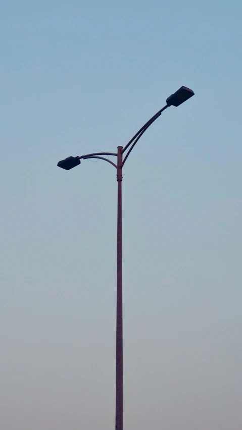 a tall lamp post sits near a street light