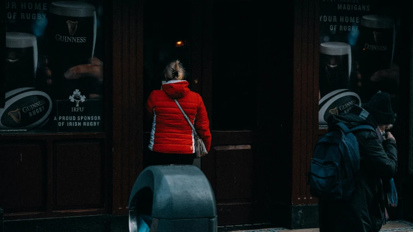 woman in red jacket in the dark standing on a city street