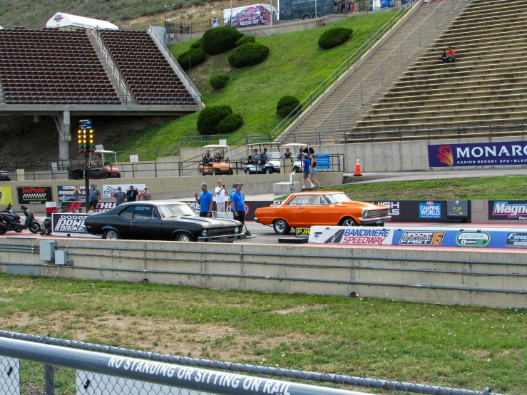 cars drive down a track next to the stadium