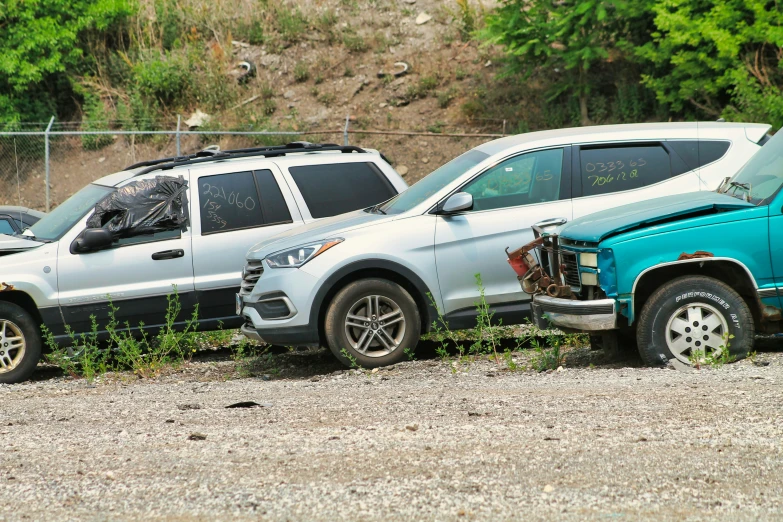 two cars are parked in a junk pile with trees in the background