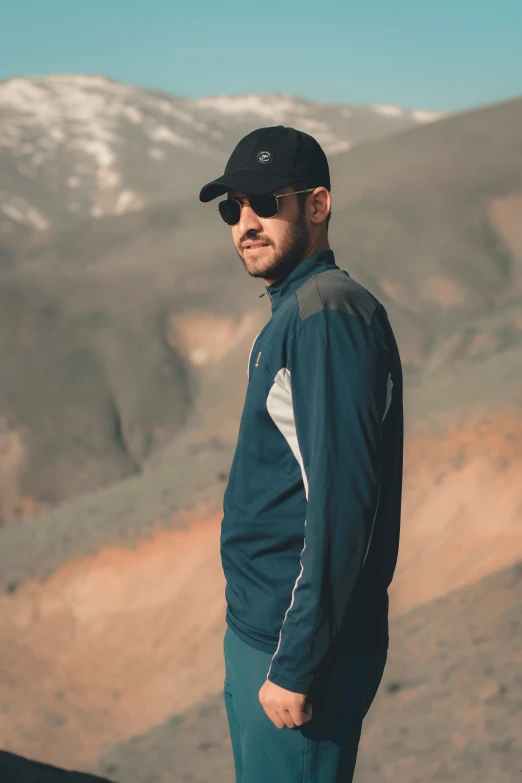 a man in a blue jacket stands on a mountain