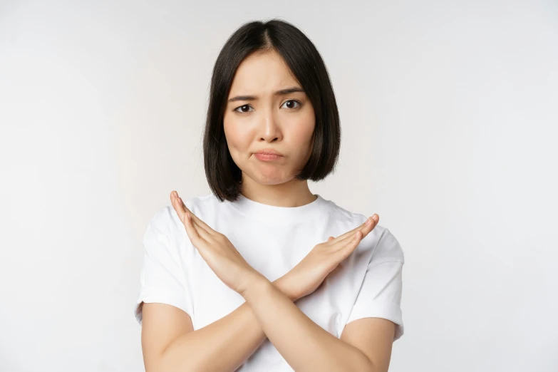 an asian woman wearing a white shirt holding her hands together in prayer position