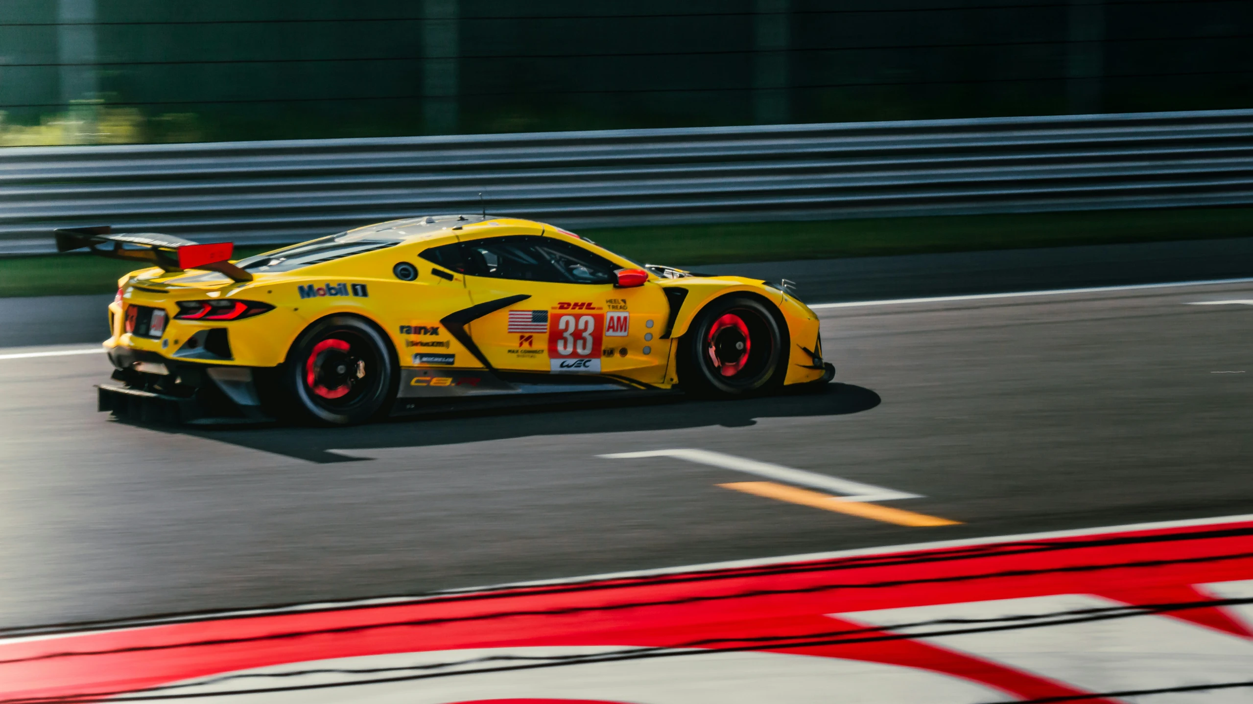 a yellow car races along the track, with red stripe