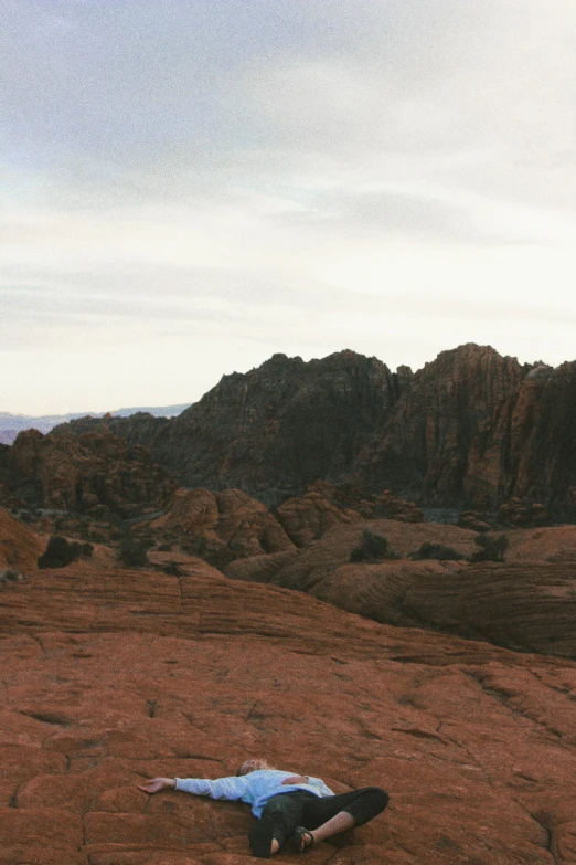 a person lying on the ground near a mountain