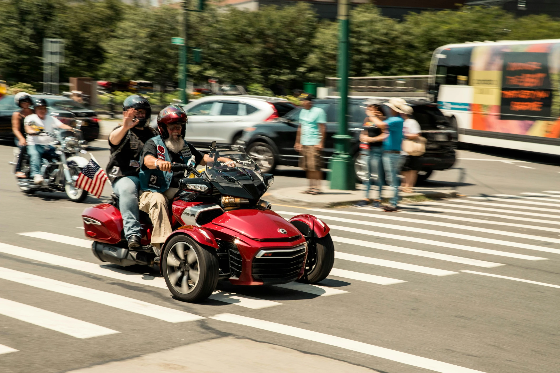 two people riding red motorcycle down the street