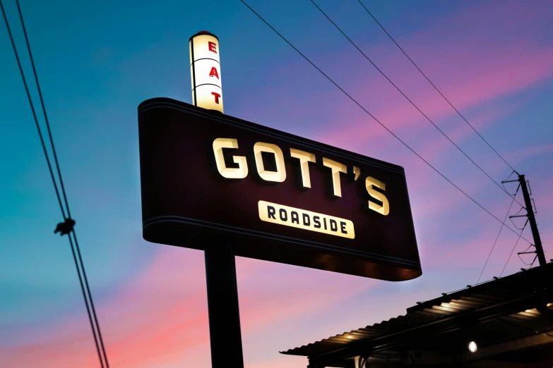 a lit up restaurant sign at dusk with the sky in the background