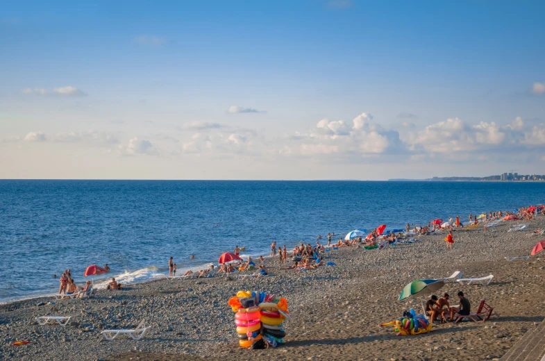 several people on the beach with an umbrella and many inflatables