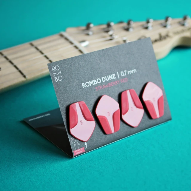 a guitar pick set sits next to the strings of a guitar