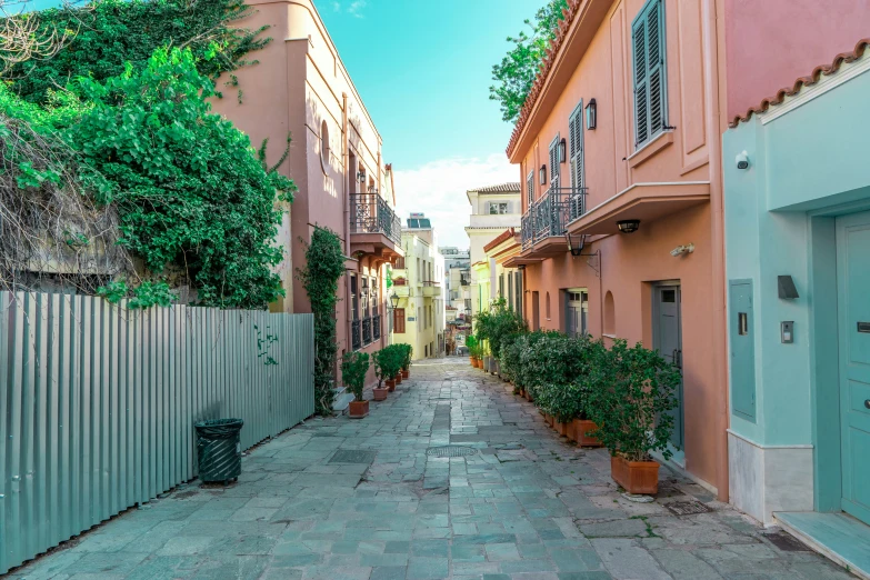 a narrow paved alley with tall pink buildings on either side