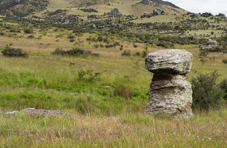 some very large rocks in a big grassy field