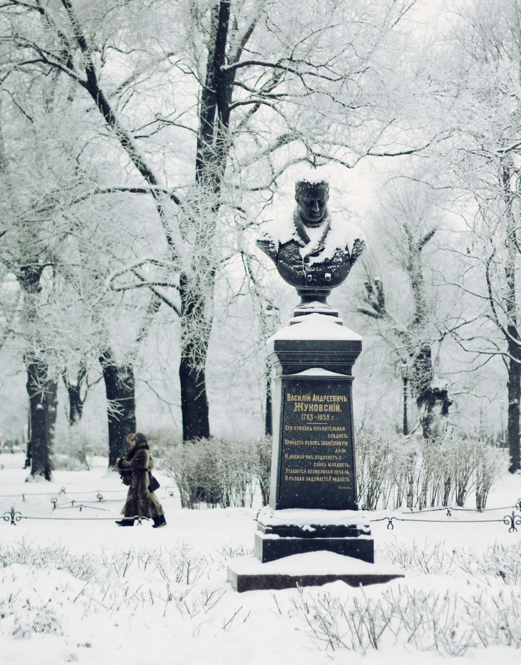 a statue sitting on top of a park covered in snow