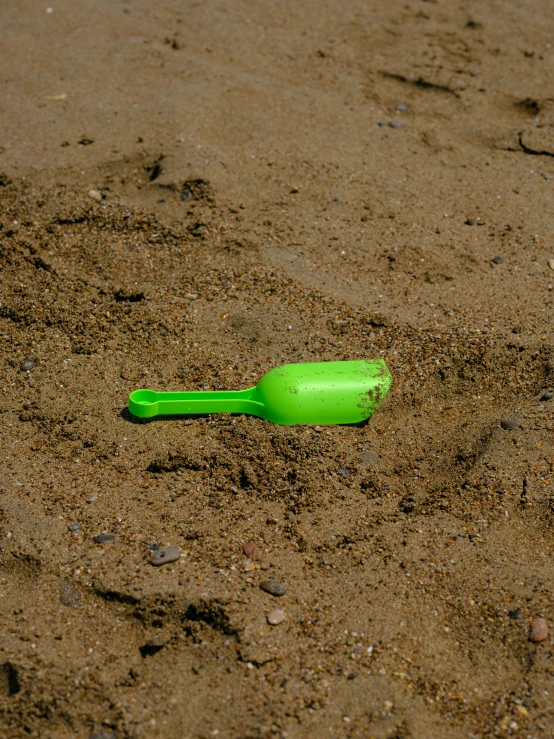 a plastic green bottle is in the sand