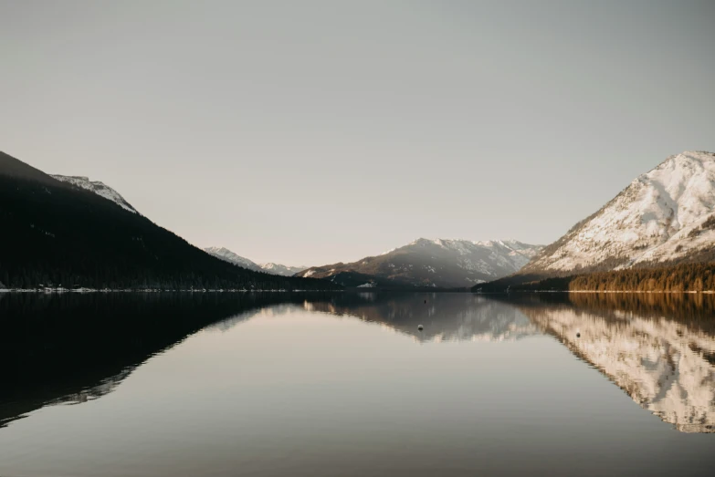 the view over a lake with snow covered mountains in the background