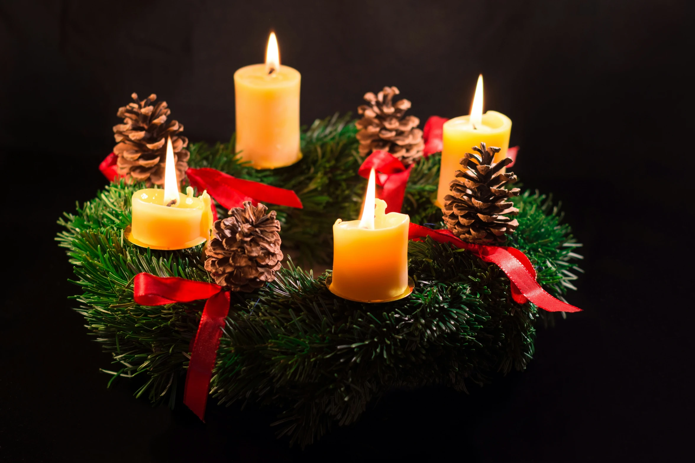 candles on pine cones with red ribbon and pine cones