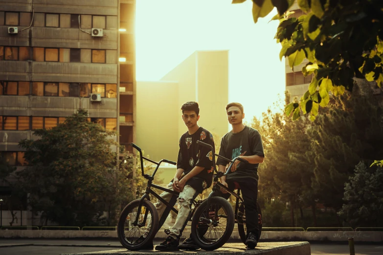 two guys with bikes in front of large buildings