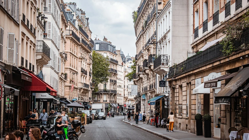 a narrow cobble stone street is flanked by tall buildings