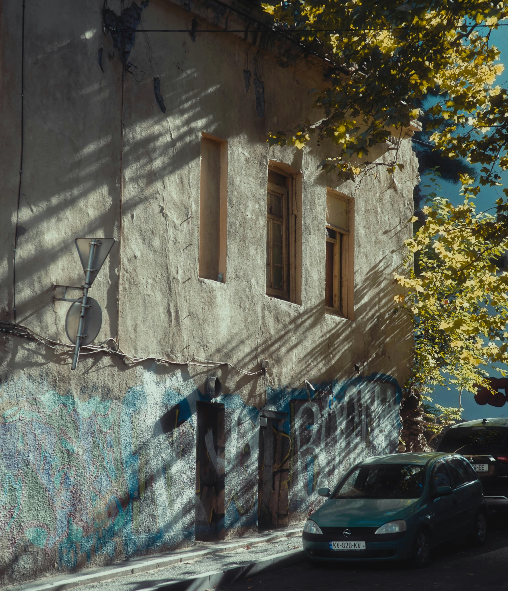 a graffiti covered wall with a parked car on the side