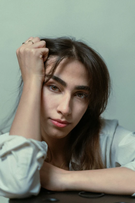 a beautiful young woman sitting at a table with her arms resting against her head