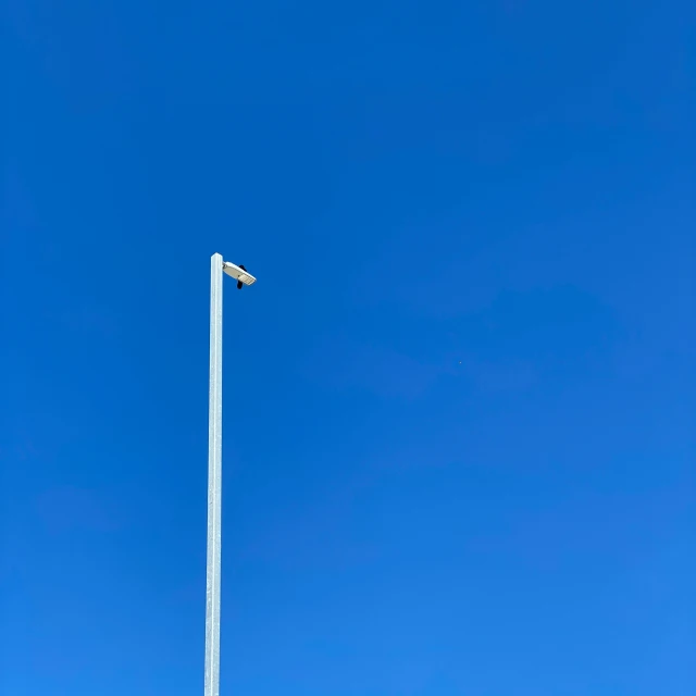 a traffic light is standing in the clear blue sky