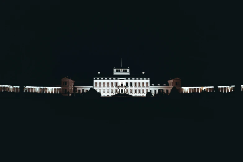 a white building sits in the middle of a dark field