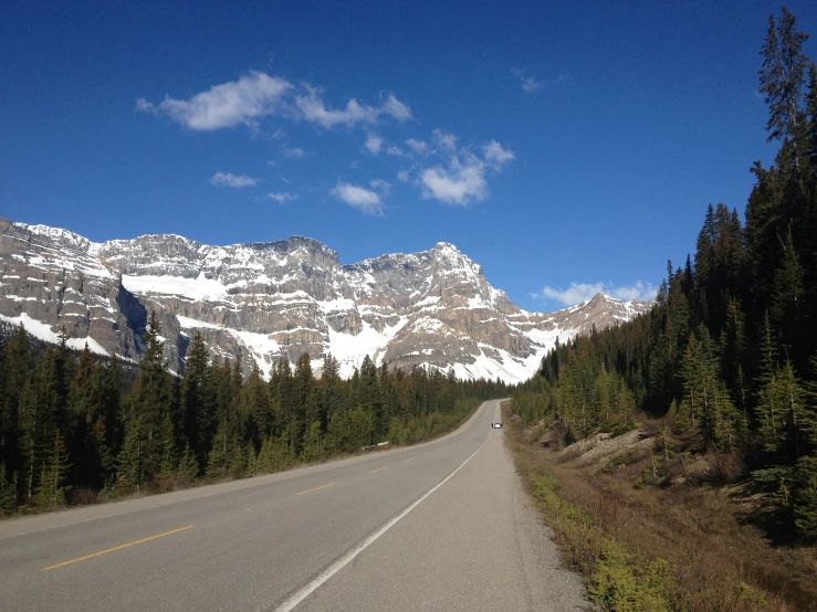 a scenic, snow capped mountain landscape seen from the side of a road