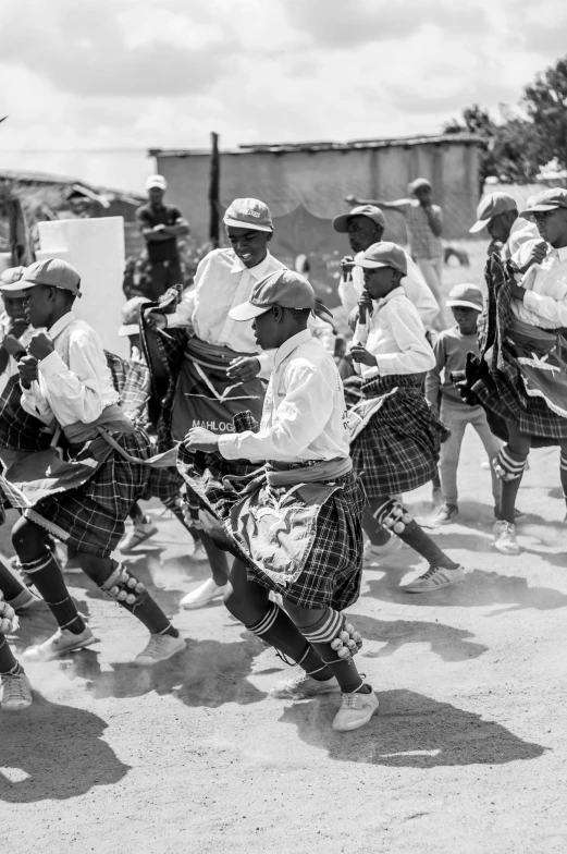 a bunch of people in kilts playing with a kite