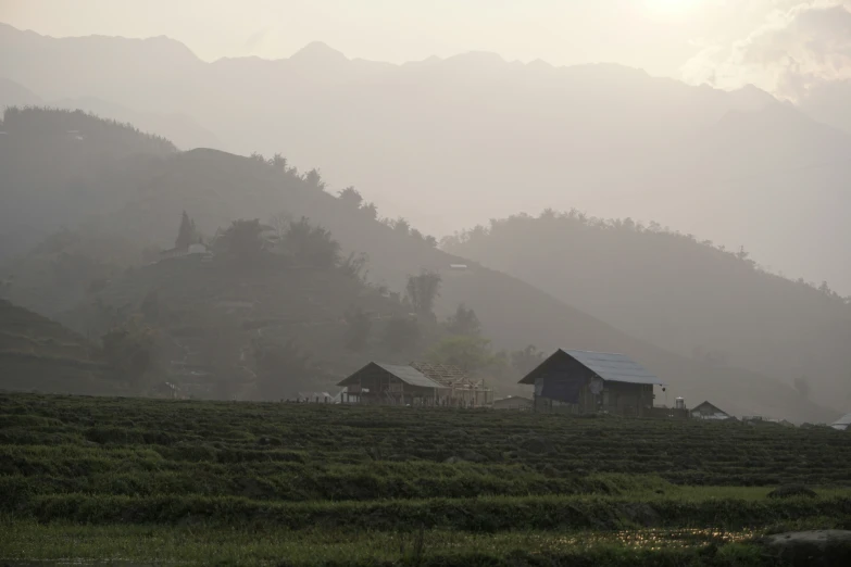 a farm field with houses on the hillside