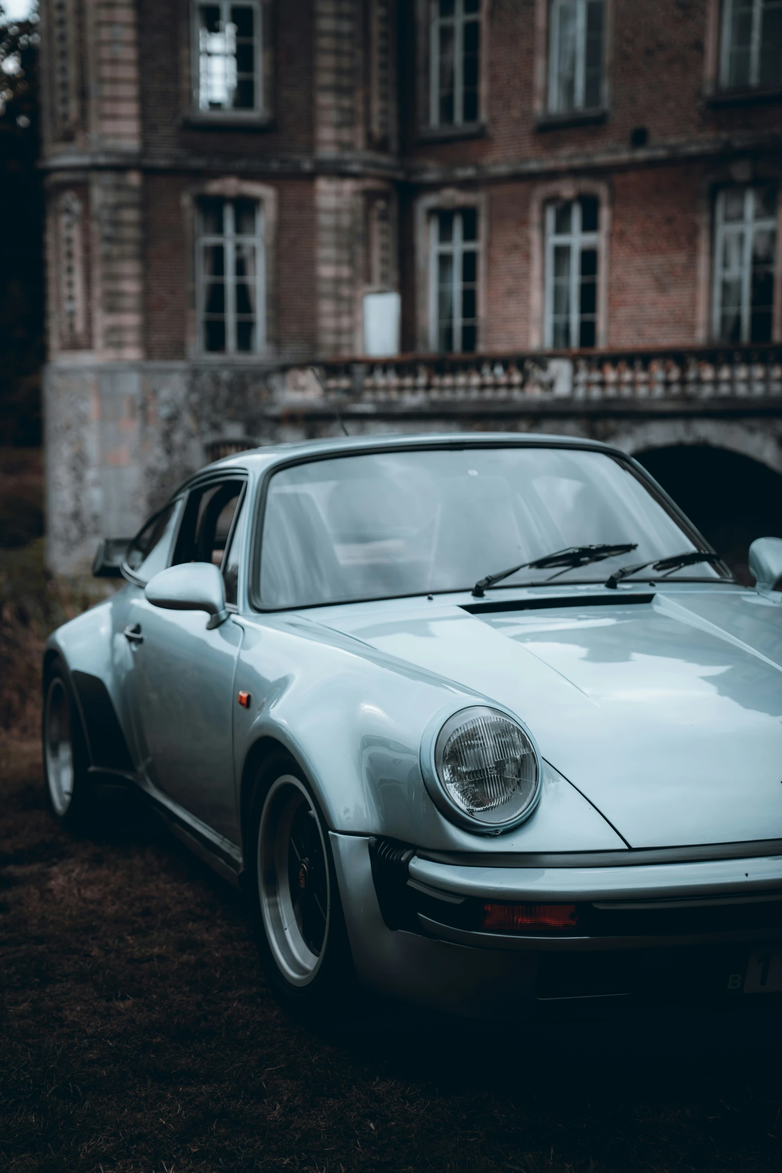 a blue porsche sports car parked in front of an old building