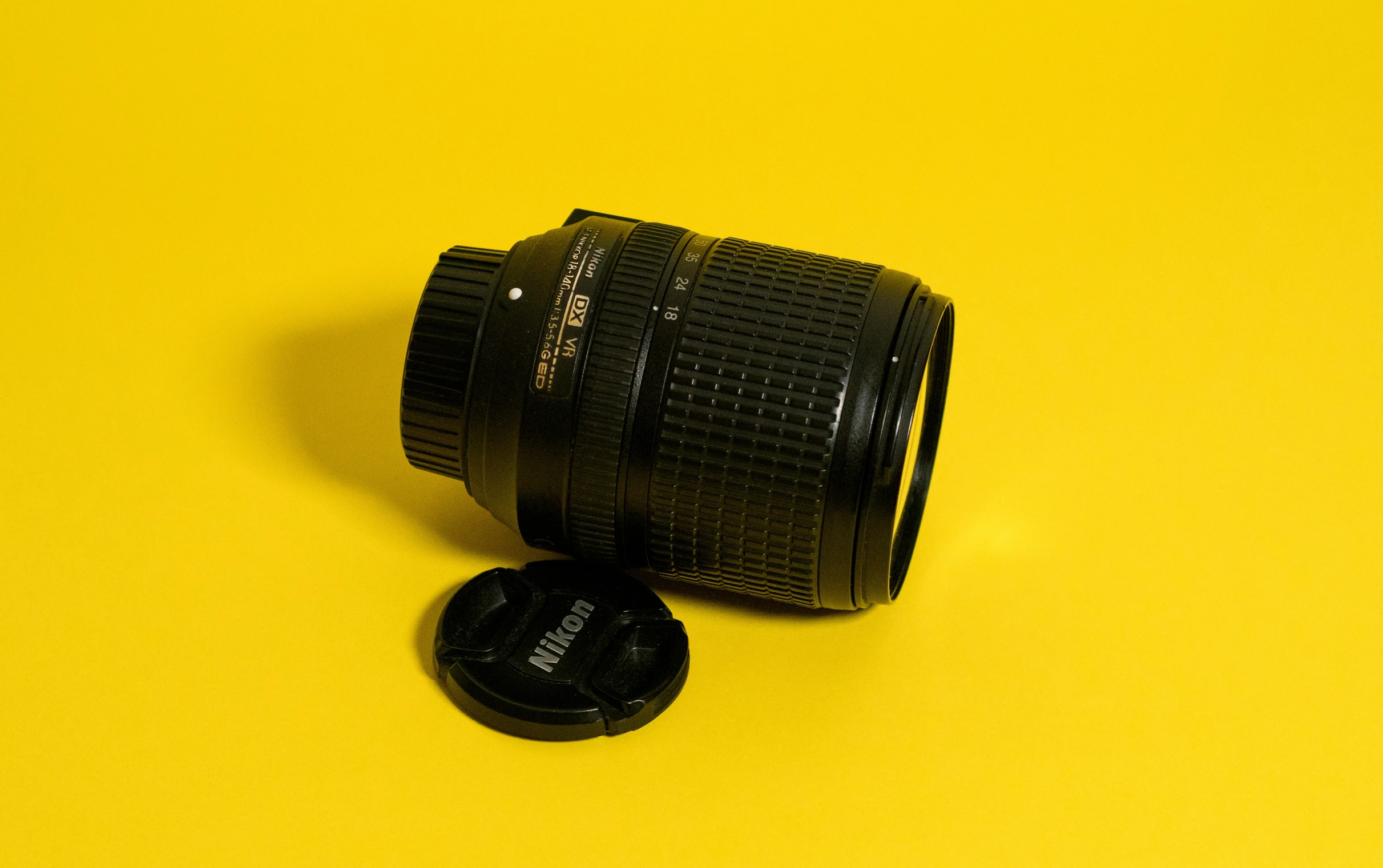 a camera lens sits on a tripod on yellow background