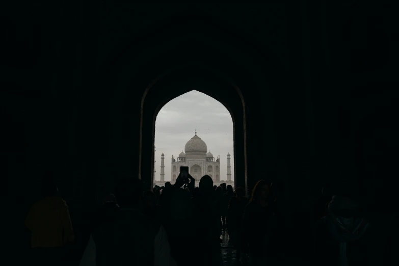 people stand in the shadows of an archway with a building in the background