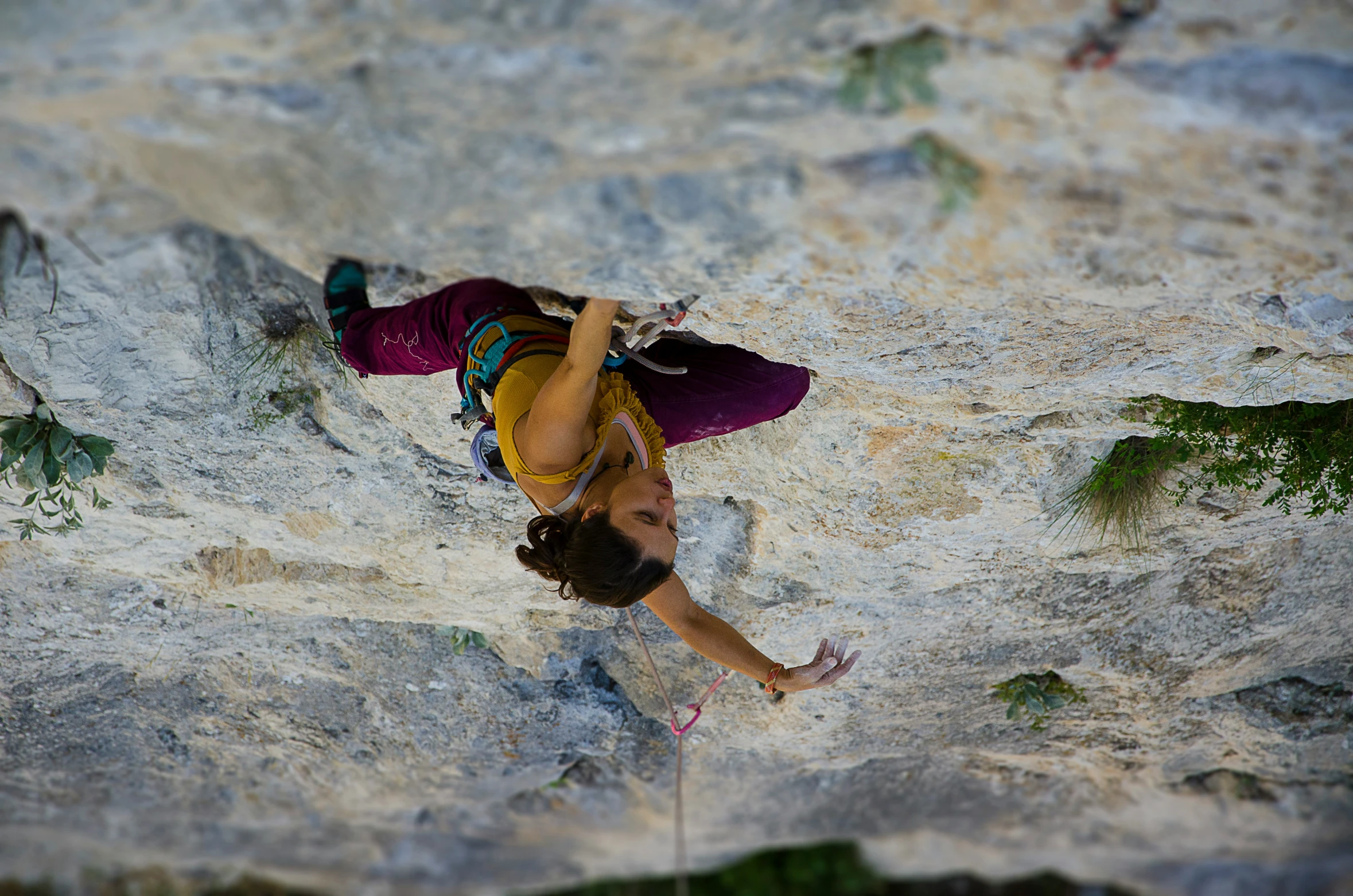 a man with a multi - colored shirt is climbing up a rock