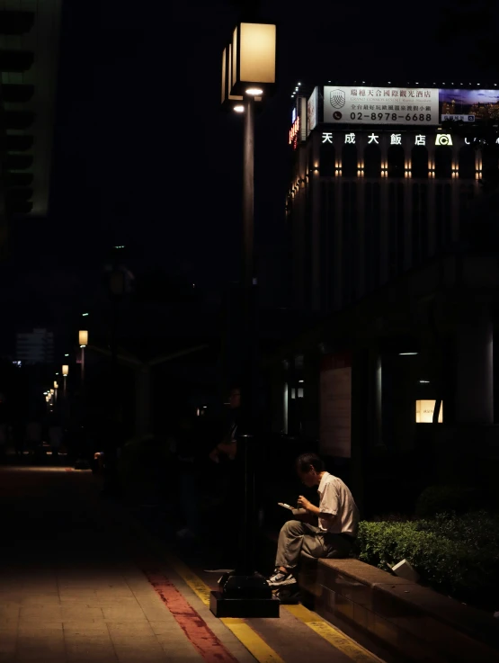 a man sitting on the curb by his laptop