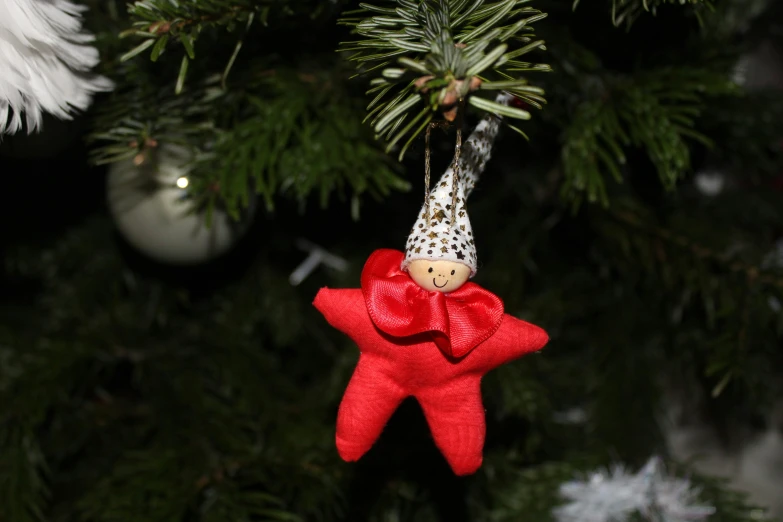 a close up of a red decoration hanging on a tree