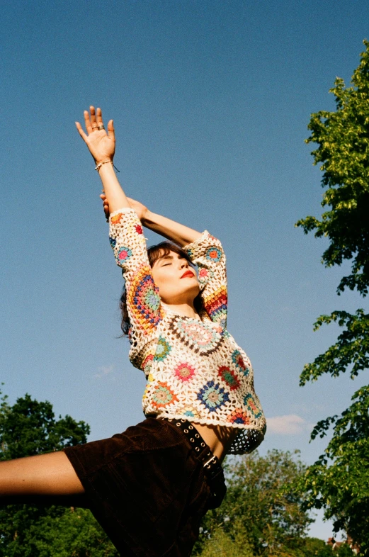 a young lady is in mid air and reaching up toward the sky