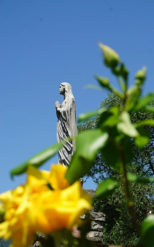 a statue of an angel is perched near some flowers