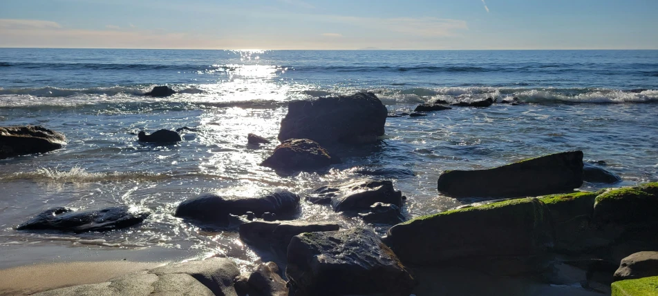 an image of a beach with some rocks on the shore