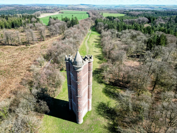 an old stone tower surrounded by trees and some tall grass