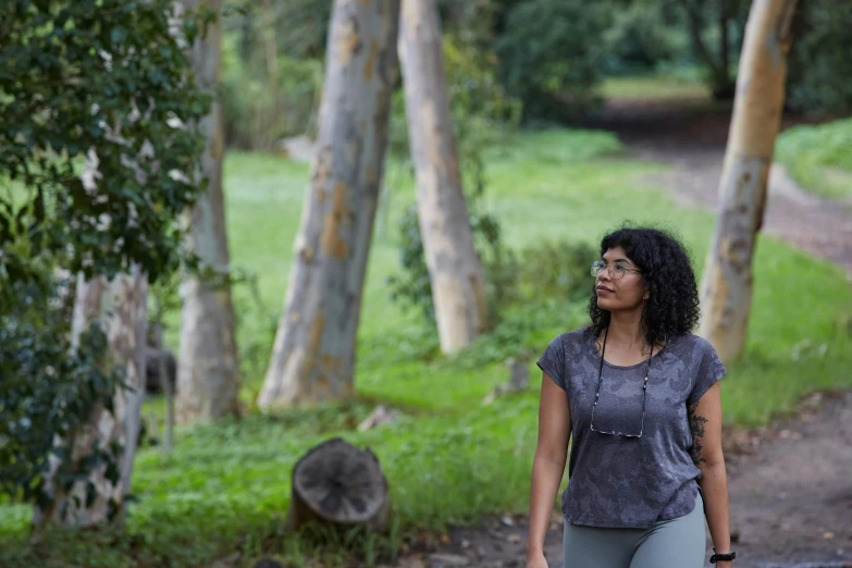 the woman walks alone in the woods holding an umbrella