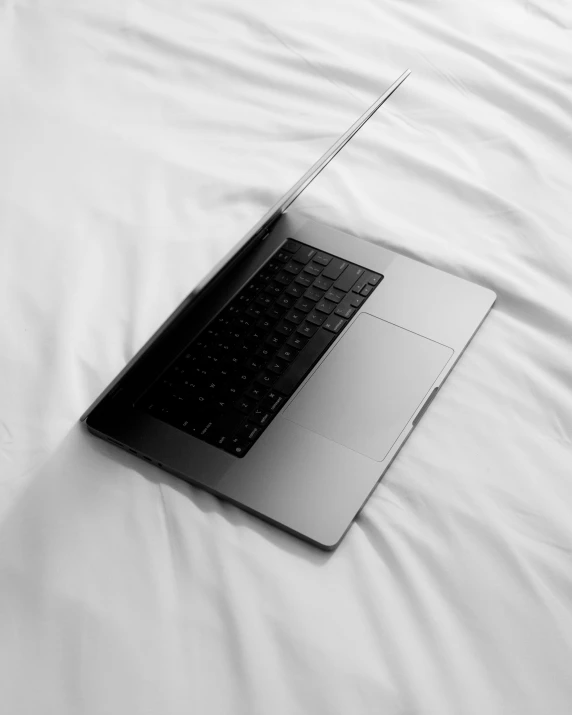 a laptop sitting on a white sheet in a bed
