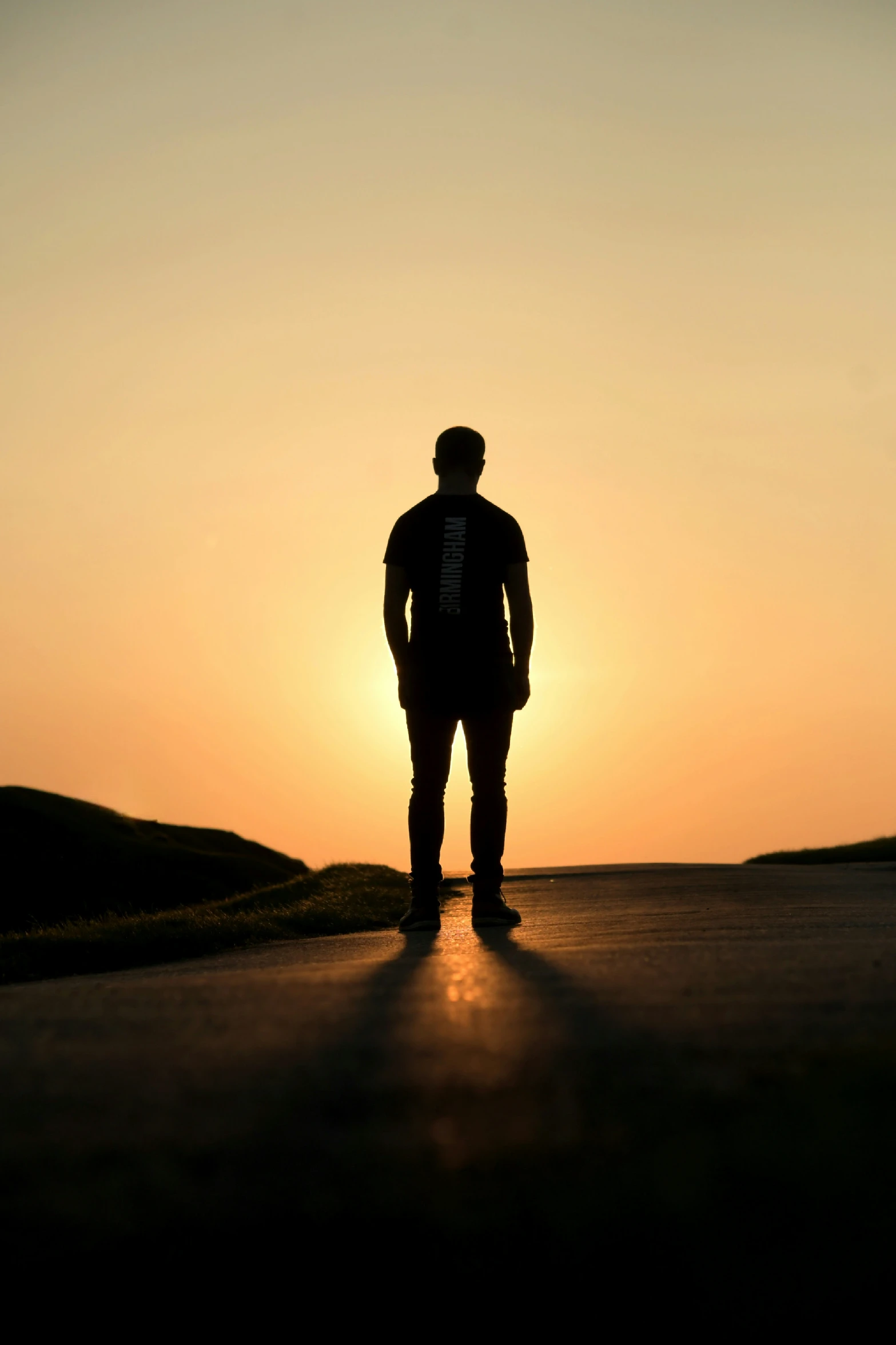 a silhouette of a man looking at the setting sun