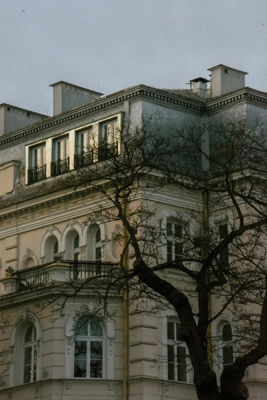 an old building is behind some bare trees